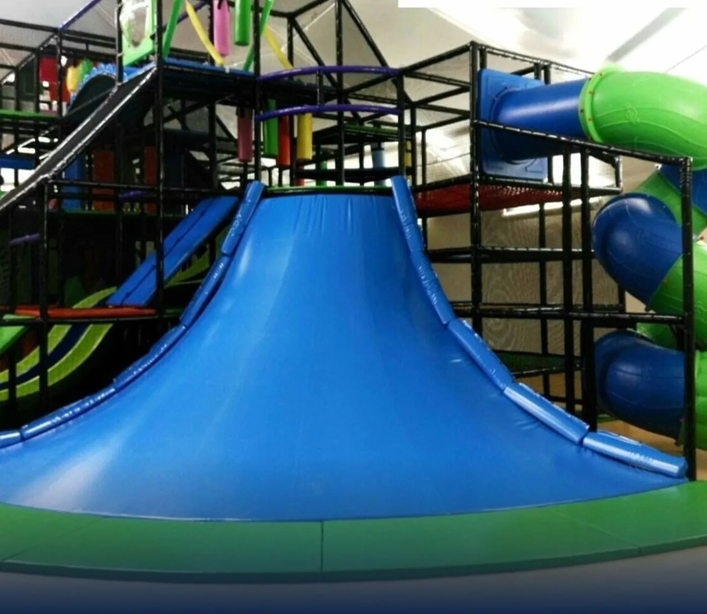 Three-level indoor playground with central volcano and slides